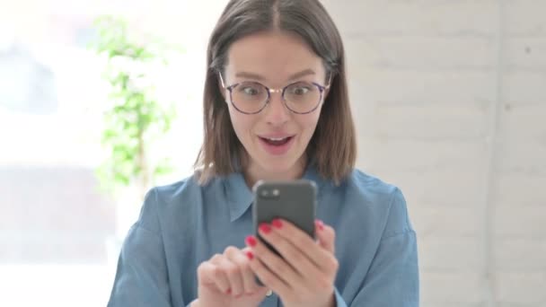 年轻女性在办公室用智能手机庆祝成功的肖像 — 图库视频影像