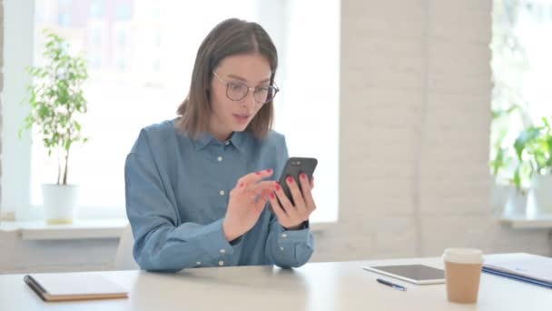 Wanita muda Merayakan Sukses di Smartphone di Kantor — Stok Video