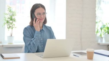 Dizüstü bilgisayarlı Genç Kadın Akıllı Telefonla Konuşuyor 