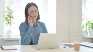 Dizüstü bilgisayarlı Kızgın Genç Kadın Akıllı Telefonla Konuşuyor 