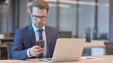 Dizüstü bilgisayarlı bir iş adamı telefonda konuşuyor. 