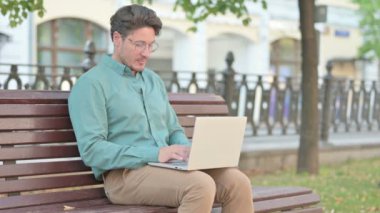 Dizüstü bilgisayarı olan bir adam Bench 'te duruyor ve gidiyor. 