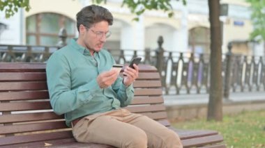 Park Bench 'teki akıllı telefondan online ödeme yapan adam. 