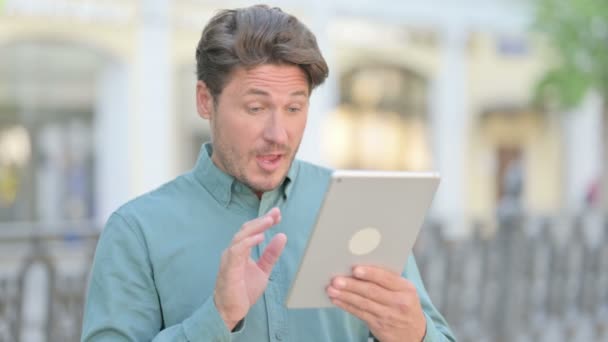 Videollamada en tableta por hombre de mediana edad al aire libre — Vídeos de Stock