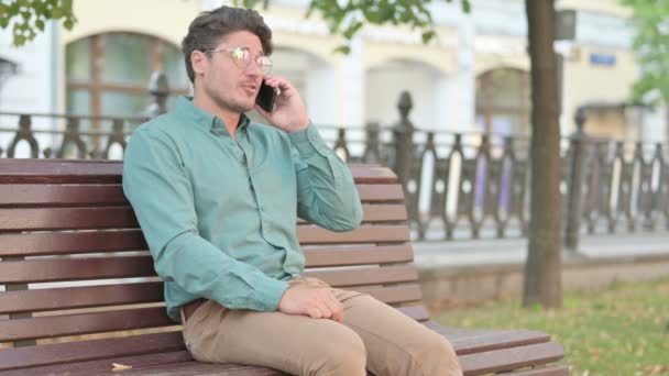 Homme parlant au téléphone pendant qu'il était assis sur le banc — Video