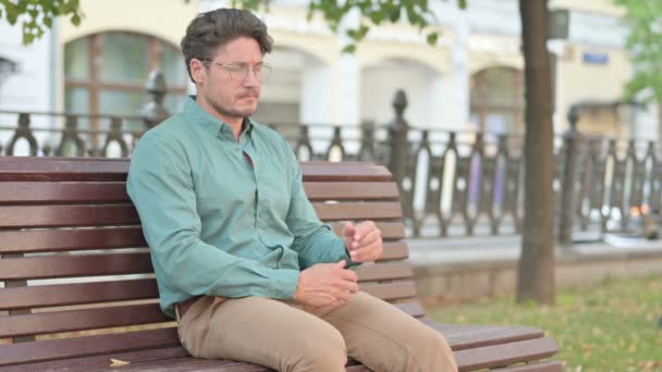 Homme se sentant inquiet tandis que assis sur le banc extérieur — Video