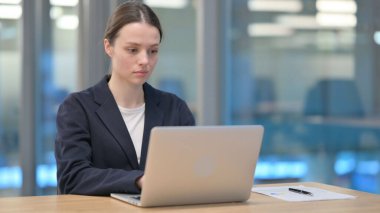 Ofisteki dizüstü bilgisayarda çalışan genç iş kadını