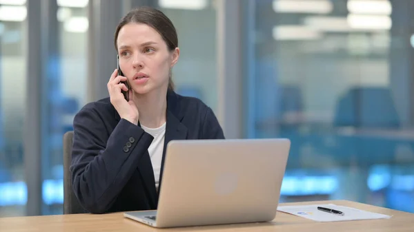 Ung affärskvinna Prata i telefon när du använder laptop — Stockfoto