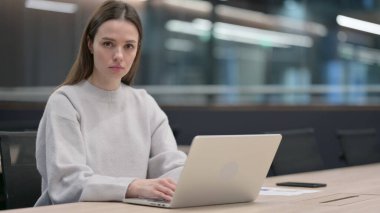 Dizüstü bilgisayar üzerinde çalışırken Kameraya Bakan Kadın