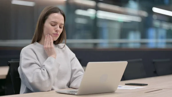 Жінка з зубним болем під час роботи на ноутбуці — стокове фото