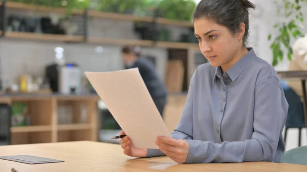 Ung indisk kvinna läser papper på jobbet — Stockfoto