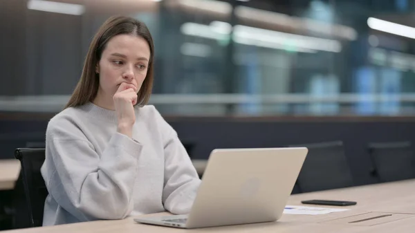 Жінка думає під час використання ноутбука на роботі — стокове фото