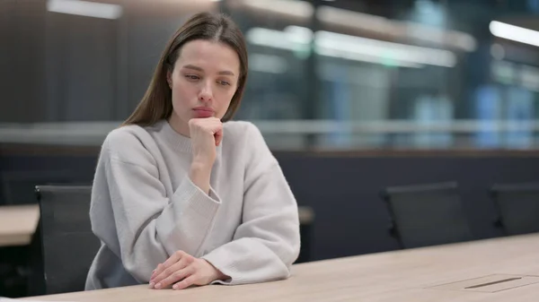 Pensive жінка сидить в офісі і мислення — стокове фото