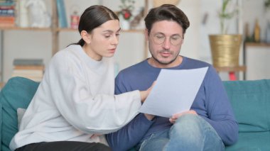 Genç Karışık Irk Çifti Koltukta Birlikte Belge Okuyor 