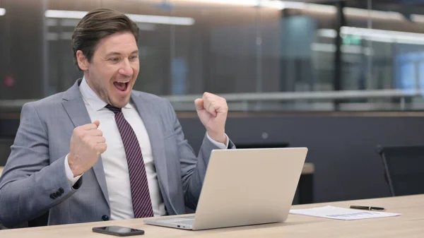Uomo d'affari di mezza età con computer portatile che festeggia in ufficio — Foto Stock