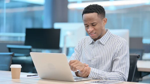 Jeune homme d'affaires africain avec ordinateur portable ayant la douleur au poignet — Photo