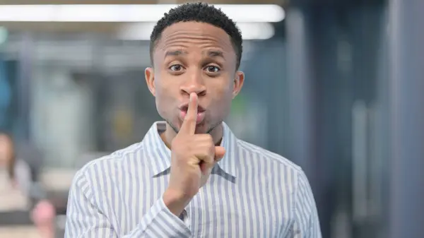 Porträt eines afrikanischen Geschäftsmannes mit dem Finger auf den Lippen, stilles Zeichen — Stockfoto