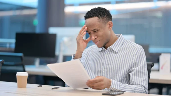 Un om de afaceri african reacționează la pierderi în timp ce citește documente — Fotografie, imagine de stoc