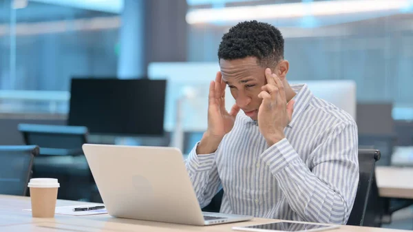 Joven empresario africano con portátil con dolor de cabeza — Foto de Stock