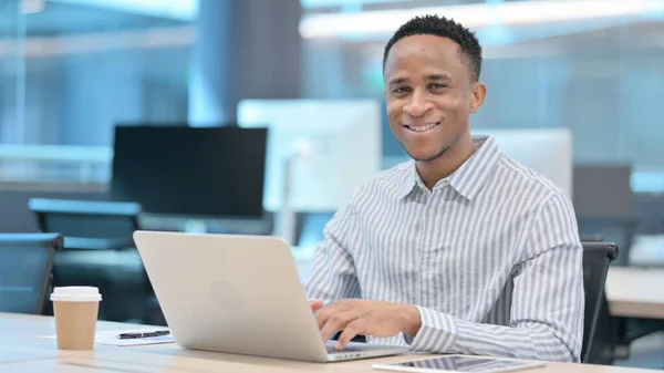 Homme d'affaires africain avec ordinateur portable souriant à la caméra — Photo