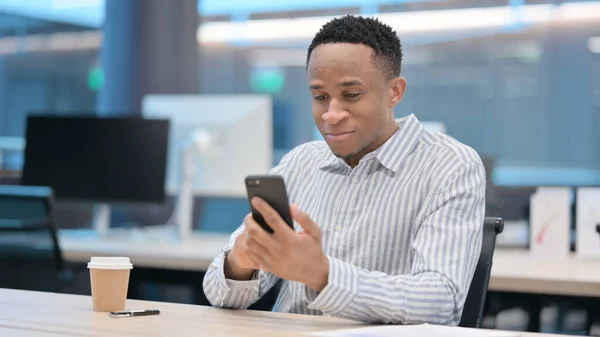 Afrikanischer Geschäftsmann surft mit Smartphone im Internet — Stockfoto