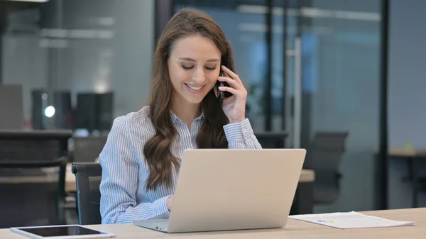 Young Businesswoman Berbicara di Smartphone saat menggunakan Laptop — Stok Foto