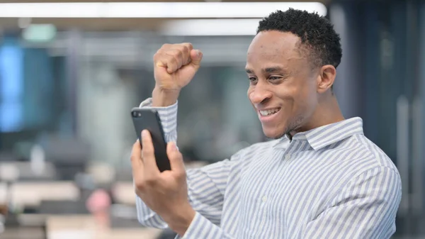 Porträt eines afrikanischen Geschäftsmannes beim Feiern auf dem Smartphone — Stockfoto