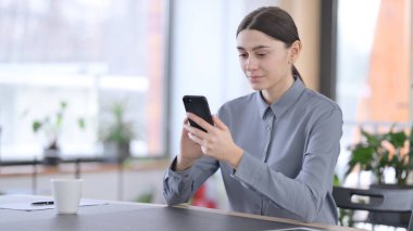 İş yerinde akıllı telefon kullanan çekici Latin Kadın 