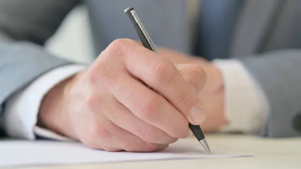 Großaufnahme eines Geschäftsmannes, der mit Stift auf Papier schreibt — Stockfoto