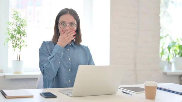 Жінка з ноутбуком відчуває шок в сучасному офісі — стокове фото