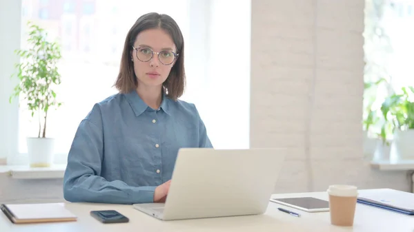 Ofiste dizüstü bilgisayar kullanırken Kameraya Bakan Kadın — Stok fotoğraf