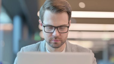 Ofisteki dizüstü bilgisayarda çalışan genç adama yakın çekim 