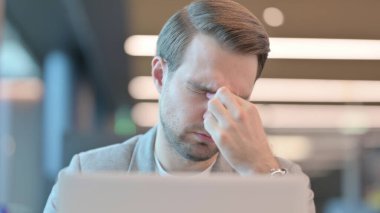 Dizüstü bilgisayarlı genç adamın baş ağrısı var. 