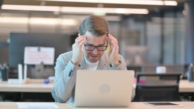 Dizüstü bilgisayarı olan genç adam baş ağrısı çekiyor. 