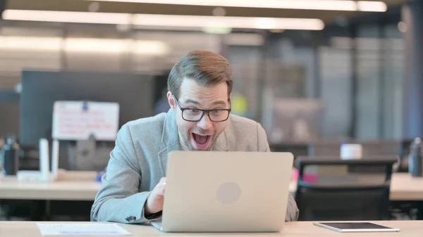 Succès Jeune homme Célébration sur ordinateur portable au bureau — Photo