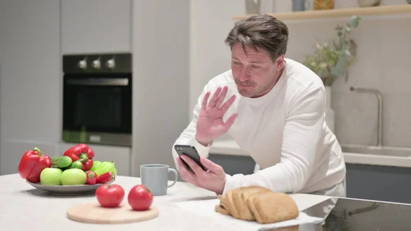 Moyen Age Homme Faire appel vidéo sur Smartphone dans la cuisine — Photo