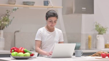 Genç Hintli Kadın Mutfakta Dizüstü bilgisayarda çalışıyor