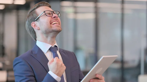 Retrato de un joven empresario celebrando el éxito en la tableta — Foto de Stock