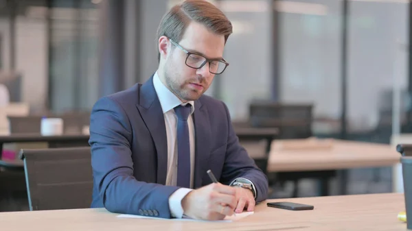 Jeune homme d'affaires pensif écrivant sur papier, pensant — Photo