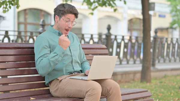 Homme adulte mature se sentant surpris en utilisant un ordinateur portable sur le banc — Photo