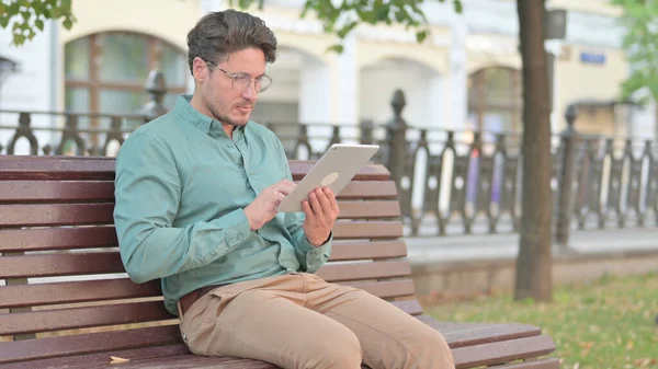Starší dospělý muž pomocí tablet zatímco sedí na lavičce v parku — Stock fotografie