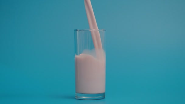 Slow Motion of Pouring Milk in Glass, Blue Background — Stok video