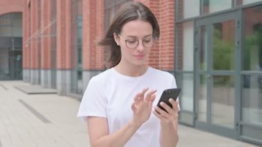 Genç Kadın Smartphone 'da internette gezinirken sokakta yürürken