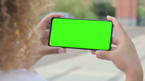 Afrikaanse vrouw op zoek naar smartphone met groene chroma scherm — Stockvideo