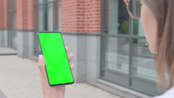 Walking vrouw met behulp van smartphone met groene scherm — Stockvideo