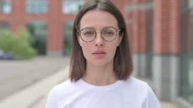 Başparmaklarını gösteren genç bir kadın, açık hava.