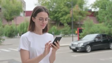 Genç Kadın Smartphone 'da internette gezinirken sokakta yürürken