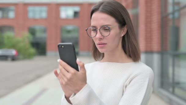 Молодая женщина реагирует на потерю на смартфоне — стоковое видео