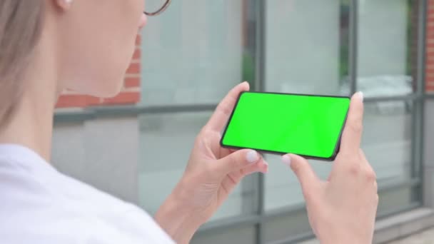 Ходячая женщина, смотрящая смартфон с зеленым хроматическим экраном — стоковое видео