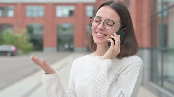 Молодая женщина разговаривает на смартфоне, на открытом воздухе — стоковое видео